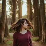 A young woman twirls in a forest, capturing the essence of nature and freedom.